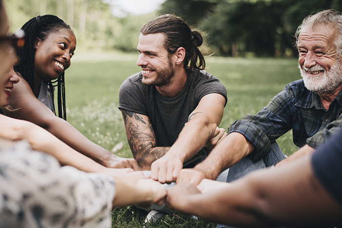 Happy people stacking hands together in the park